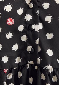 Tecido preto com um padrão floral apresentando flores brancas e vermelhas. Inclui botões redondos e uma bainha com babados. Textura suave e leve.