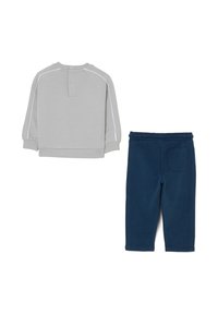 Felpa grigia con accenti bianchi, collo rotondo e maniche lunghe abbinata a pantaloni della tuta blu navy con vita elastica e tasca posteriore.