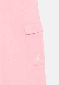 Pink cotton shorts with a side pocket, featuring a white embroidered Jordan logo. Smooth texture, casual design, and above-the-knee length.
