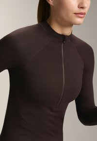 Maglione zip-up marrone scuro con collo alto, caratterizzato da un motivo a coste testurizzato e maniche raglan.