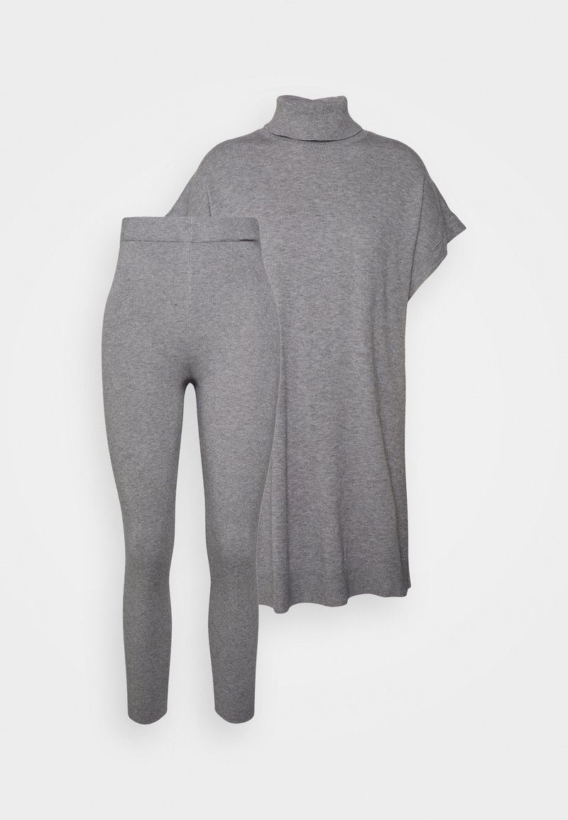 Cape en maille gris à col roulé avec manches courtes, associée à des leggings ajustés taille haute assortis, présentée sur fond blanc.