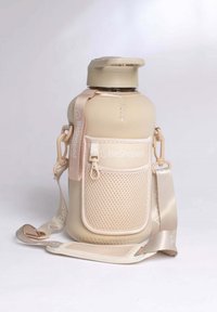 Bouteille d'eau beige avec une surface texturée, un couvercle amovible, une poche en maille et une sangle réglable arborant la marque "BeShaped" dans des tons clairs.