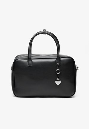 Schwarze rechteckige Handtasche mit abgerundeten Ecken, zwei Griffen und einem hängenden silbernen herzförmigen Anhänger vor einfachem Hintergrund.