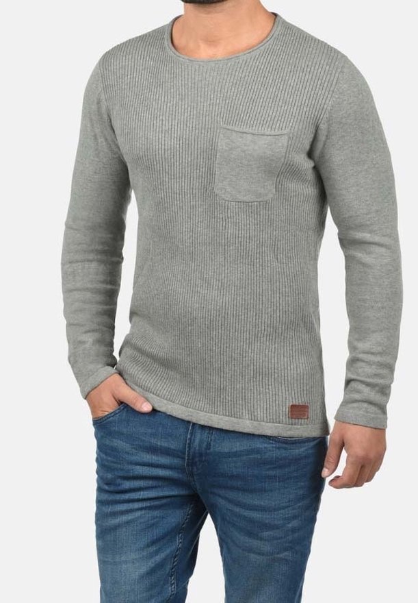 Grauer, gerippter Pullover mit langen Ärmeln und Rundhalsausschnitt, mit einer Brusttasche und einem kontrastierenden braunen Lederetikett am Saum.