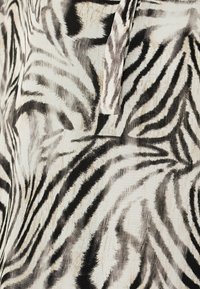 Materiał w paski zebry w czerni i bieli o miękkiej strukturze. Posiada faliste linie i subtelny połysk, co zwiększa atrakcyjność wizualną.
