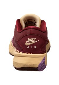 Le sneakers Nike Air presentano una tomaia sintetica color bordeaux, accenti color crema e una suola testurizzata con un dettaglio viola nel tallone.