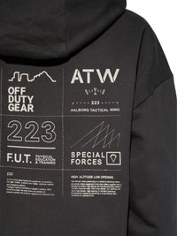 Sort hættetrøje med hvidt taktisk tema tekst og grafik, herunder "OFF DUTY GEAR", "ATW", "223", "SPECIAL FORCES" og militærrelaterede beskrivelser.