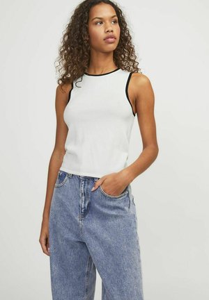 Top sin mangas blanco con ribete negro, hecho de una tela suave; combinado con unos jeans de mezclilla azul de cintura alta con bolsillos laterales.