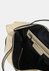 Borsa a tracolla in pelle beige con interno in tessuto nero, tasca con cerniera aperta e cursore della cerniera dorato all'interno.