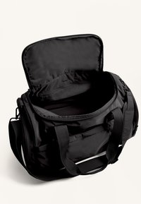 Zwarte duffeltas gemaakt van duurzaam materiaal met een ritssluiting, stevige handgrepen en een ruime binnenkant. Geen extra vakken zichtbaar.