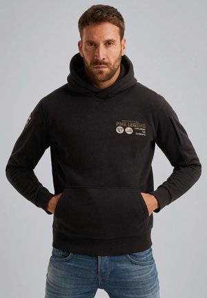 Black hooded sweatshirt made of cotton blend with a front kangaroo pocket. Features gold text and logos on the chest and left sleeve.