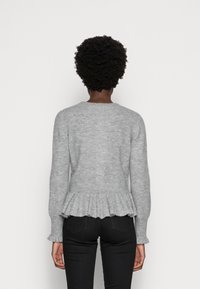 Szary dziergany sweter z baskinką, długimi rękawami i prążkowaną fakturą. Widok od tyłu pokazuje okrągły dekolt i subtelne falbanki wzdłuż dołu.