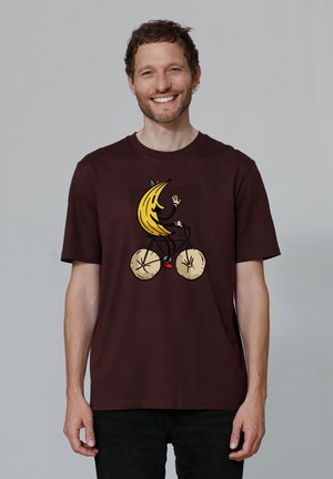 Bordeaux katoenen t-shirt met een afbeelding van een banaan die op een fiets rijdt, met gele, zwarte en groene accenten. Casual, relaxte pasvorm.