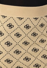Tissu tricoté beige avec un motif en diamants noirs, présentant des motifs de logo entrelacés à l'intérieur de chaque diamant. Ceinture côtelée beige en haut.