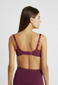 Mauve bra with adjustable straps, hook-and-eye closure, and smooth fabric, showing a simple design without padding or embellishments.