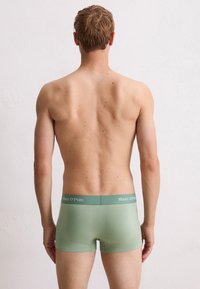 Shorts de boxeur vert menthe avec une texture lisse et une taille élastique arborant le logo "Marc O’Polo" en lettres claires, vus de l'arrière.