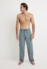 Lichte, gedessineerde pyjamabroek in teal met een herhaald ontwerp van figuren. Heeft een elastische tailleband met een trekkoord.