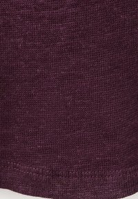 Gros plan sur un tissu tricoté violet foncé montrant un motif de point détaillé et une texture.