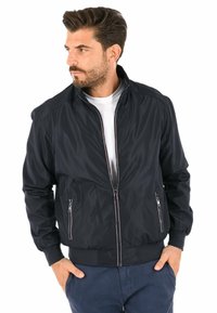 Giacca bomber navy realizzata in materiale leggero, con zipper a tutta lunghezza, tasche laterali, polsini a coste e una texture liscia.