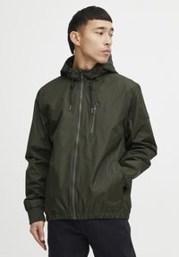 Lightweight, olive green jacket with a hood, front zipper, elastic cuffs, and adjustable drawstrings. Smooth texture and minimal design.