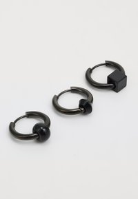 Tres pares de pendientes de aro de metal negro con diseños variados: uno con una cuenta redonda, uno liso y uno con un acento cuadrado.
