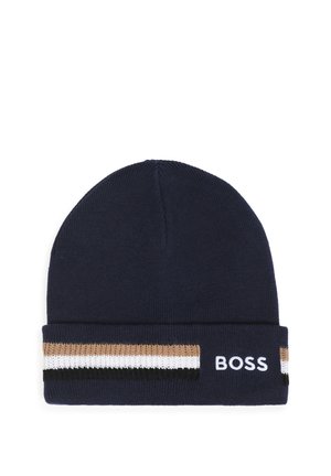 Bonnet en tricot bleu marine avec revers plié présentant des rayures horizontales beige, blanches et noires et texte brodé blanc "BOSS" sur le revers.