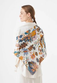Zijde sjaal met een bloemmotief in blauwe, oranje en roze tinten, driehoekige vorm en een gladde textuur, gewikkeld om een lichte blouse.
