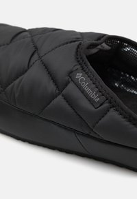 Czarne, pikowane kapcie z gładką syntetyczną cholewką, przeszyciami oraz gumową podeszwą z subtelnym logo z boku.