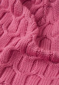 Tessuto lavorato a maglia di colore rosa con un motivo testurizzato che ricorda le onde. Le fibre appaiono morbide e spesse, evidenziando un design accogliente e intrecciato.