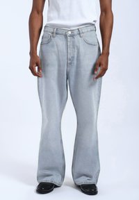 Jasnoniebieskie dżinsy rozszerzane z średnim stanem, z paskami do paska, pięcioma kieszeniami i delikatnym wyblakłym wykończeniem.