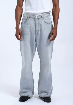 Light blue denim flared jeans with a mid-rise waist, featuring belt loops, a five-pocket design, and subtle faded detailing.