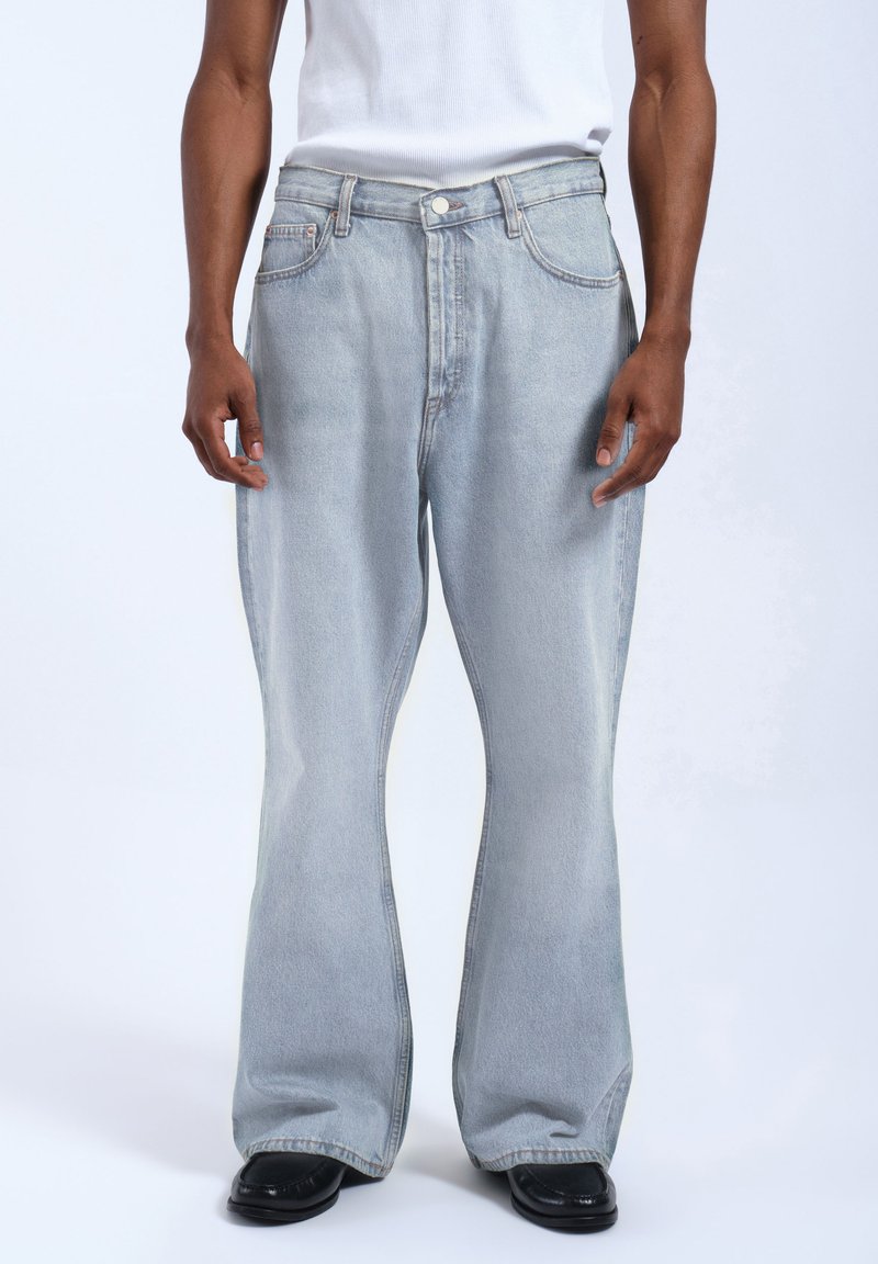 Jasnoniebieskie dżinsy rozszerzane z średnim stanem, z paskami do paska, pięcioma kieszeniami i delikatnym wyblakłym wykończeniem.