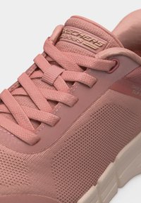 Ροζ αθλητικό παπούτσι Skechers με υφασμάτινη υφή, κορδόνια ίδιου χρώματος, επενδεδυμένο γιακά και λευκή σόλα, με λογότυπο "Skechers" στη γλώσσα.