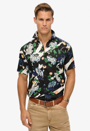 Camisa de manga corta abotonada en negro con grandes patrones florales en azul, blanco y naranja. Presenta un cuello extendido y un ajuste relajado.