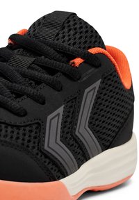 Schwarzer Sport-Schuh mit Mesh-Obermaterial, orangen Akzenten und grauen Streifen. Verfügt über schwarze Schnürsenkel und eine gepolsterte, weiße Sohle mit strukturiertem Finish.