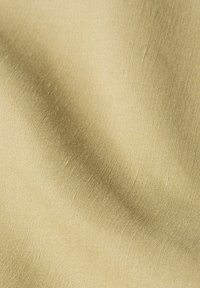 Tissu beige avec une texture lisse et un éclat subtil, présentant un motif de tissage fin. Le matériau semble léger et souple.