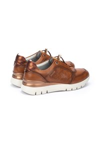 Chaussures en cuir marron avec un motif floral embossé, doublure gris clair, quincaillerie dorée, col rembourré et semelle en caoutchouc blanche.