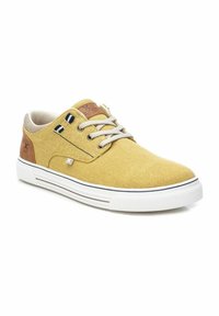 Zapatillas de lienzo amarillas con una lengüeta texturizada beige, acentos de cuero marrón, suela de goma blanca y dos rayas marinas en el lado.