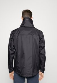 Chaqueta negra impermeable con un alto cuello, costuras estructuradas y un patrón sutil. Mangas largas con puños ajustables. Sin hardware visible.