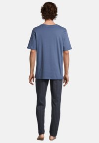 Blauwe katoenen t-shirt met een klassieke ronde hals, gecombineerd met donker gestreepte pyjamabroek in een slim fit. Zicht vanuit de achterkant.