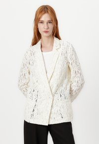 Lace blazer in off-white featuring a notched collar, single-button closure, and two front pockets. Textured with a floral lace pattern.