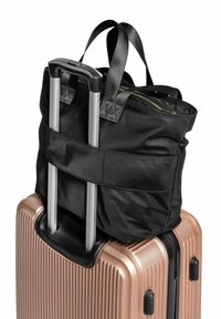 Czarna torba na ramię z dwoma uchwytami, przypięta do twardej walizki w różowym złocie. Walizka ma żłobioną teksturę i wysuwaną rączkę.