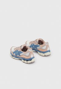 Löparskor med ovandel i mesh i vitt och mjuka rosa accenter, som har blå detaljer, tjock dämpad sula och framträdande logotyp.