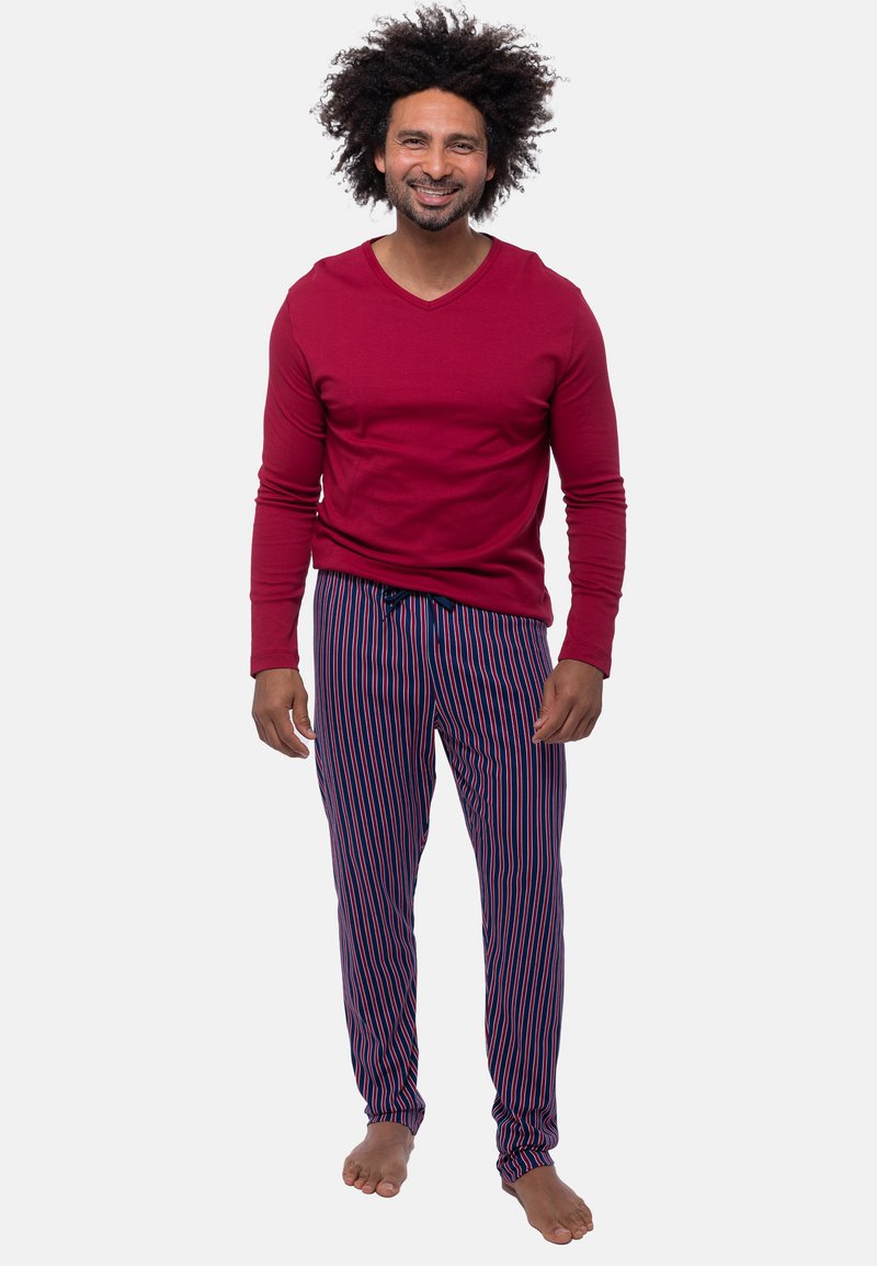 Röd långärmad t-shirt med v-ringning, kombinerad med randiga pyjamasbyxor i marinblått och rosa. Tyget verkar mjukt och bekvämt.