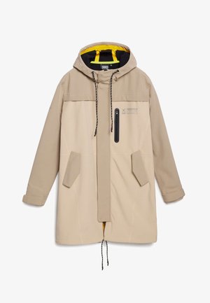 Béžová zimní bunda s kapucí, která má zipovou kapsu, šňůrky na stažení a dvě boční kapsy; uvnitř je podšívka ze žluté látky.