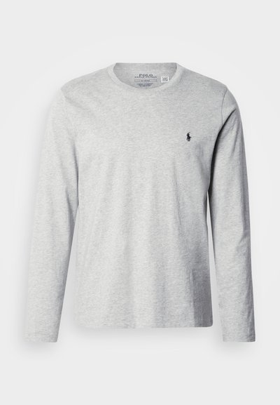 Světle šedé tričko s dlouhým rukávem vyrobené z měkké bavlny. Má kulatý výstřih a malý tmavě modrý logo na hrudi. Hladká textura, ležérní design.