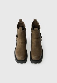 Brown faux leather ankle boots with a rounded toe, buckle detail, and textured rubber sole. Interior features a leopard print lining.