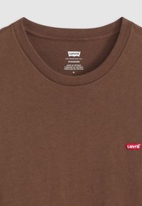 Barna Levi's kerek nyakú póló piros Levi's logóval az elején és nyomtatott címkével a nyakvonalban, közepes méret.