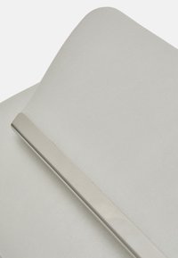 Tessuto bianco con una texture liscia, caratterizzato da una barra accentuata metallica di forma rettangolare e lucida.
