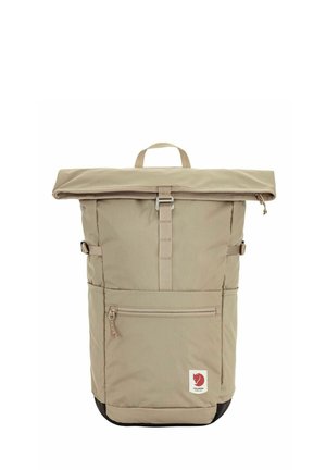 Beiger Rolltop-Rucksack mit Reißverschlusstasche vorne, zentralem Gurt mit Schnalle, seitlichen Kompressionsriemen, Tragegriff oben und rotem Fuchs-Logo in Bodennähe.